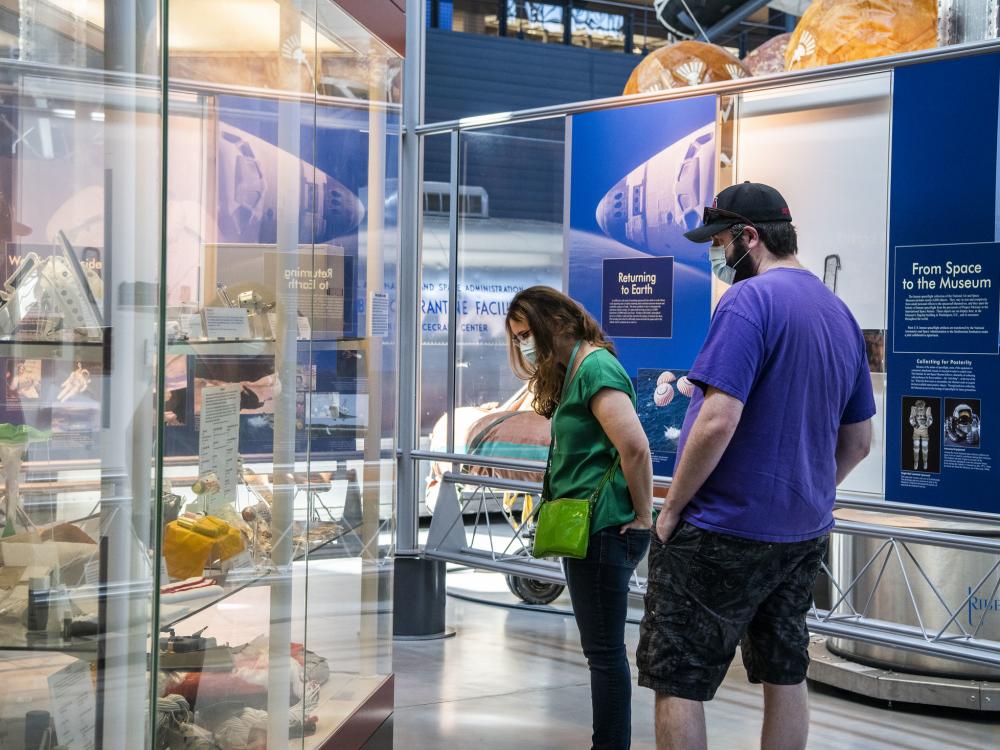 Two people stare down at artifacts in a case.