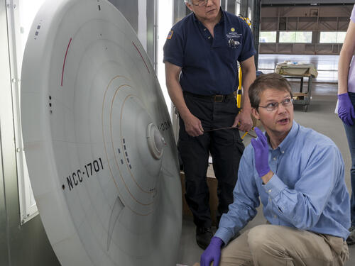 Model saucer on its side while conservators examine it. 