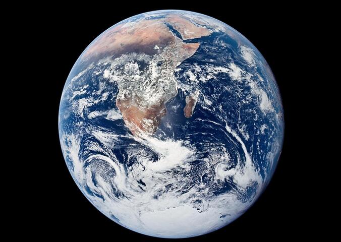 A complete circle with swirling clouds above landmasses, the Earth is seen from above.